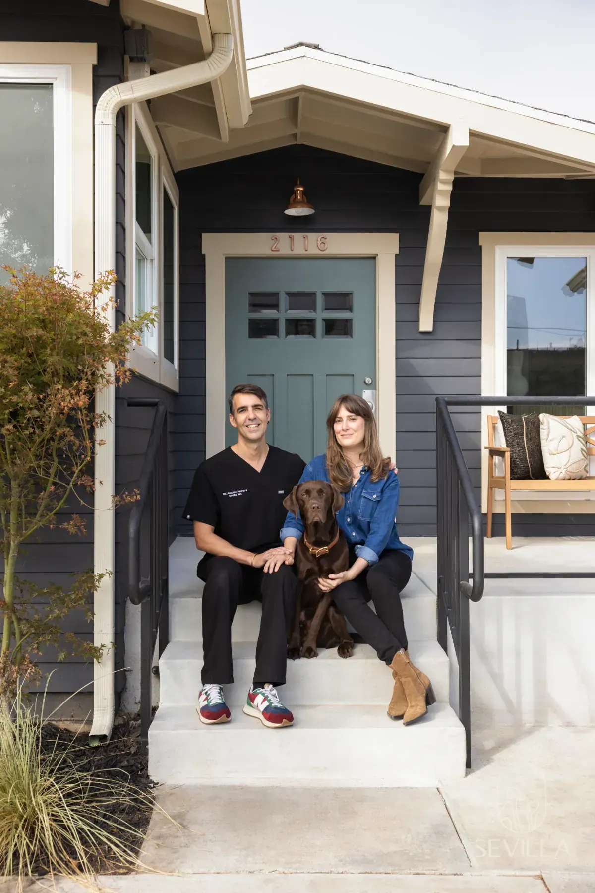 Veterinarian in scrubs sitting on clinic porch steps with a client and a dog